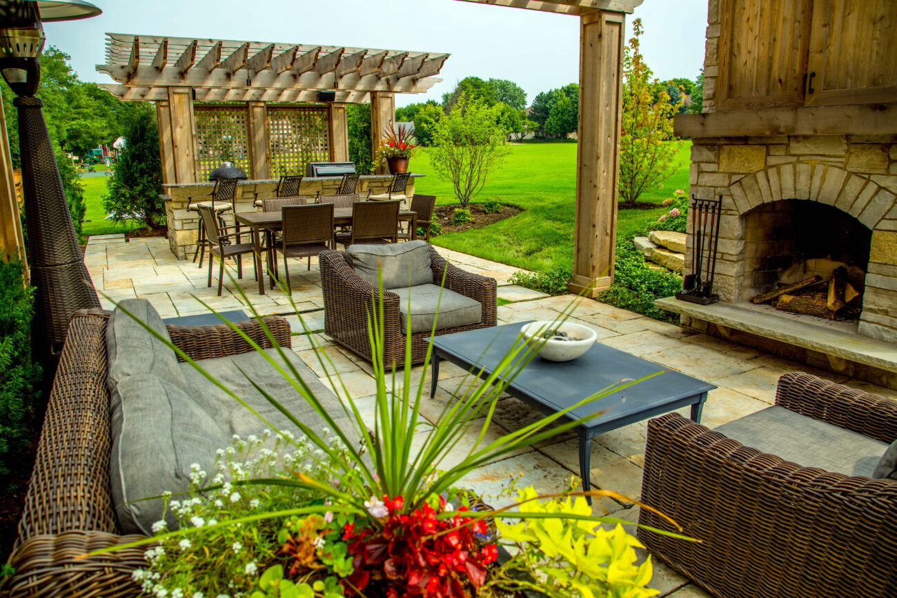 Outdoor kitchen patio with stone fireplace and wicker dining set in Naperville, IL