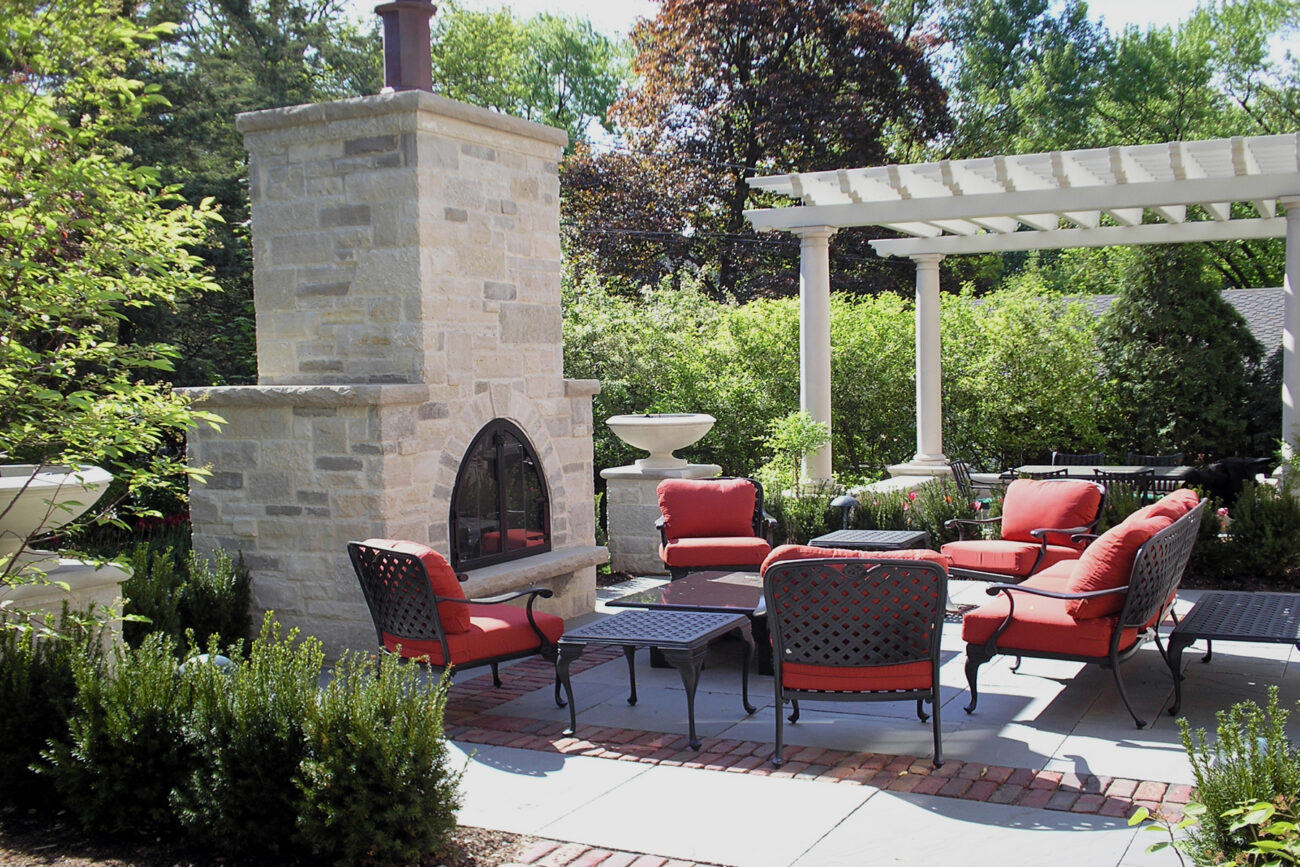 Custom stone outdoor fireplace with cushioned seating in a Naperville, IL backyard