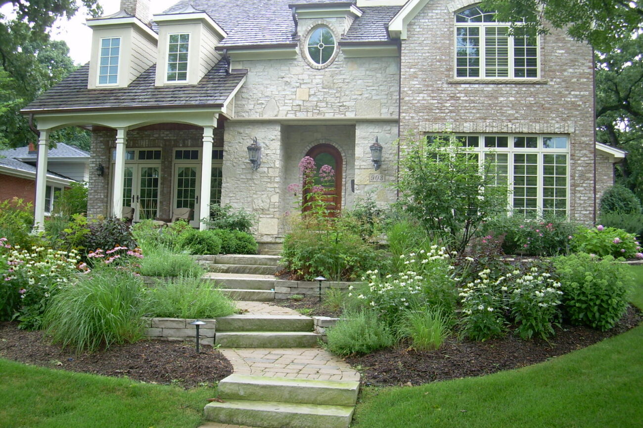 Stone front walkway and steps framed by white flowering perennials at a Naperville, IL home