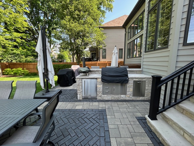 Stone outdoor kitchen with built-in grill beside a deck in Naperville, IL