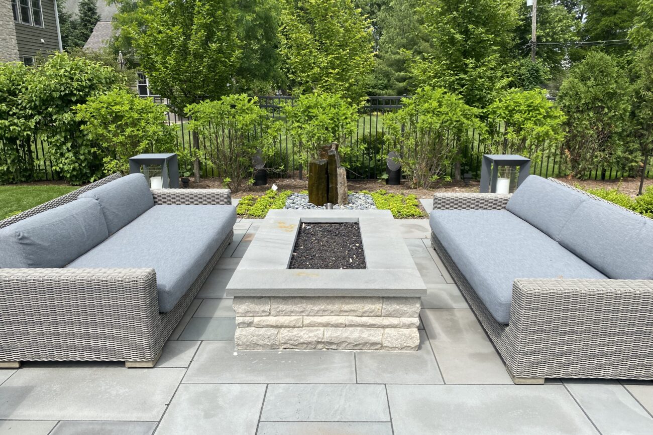 Square fire pit set between built-in cushioned benches in a Naperville, IL outdoor room