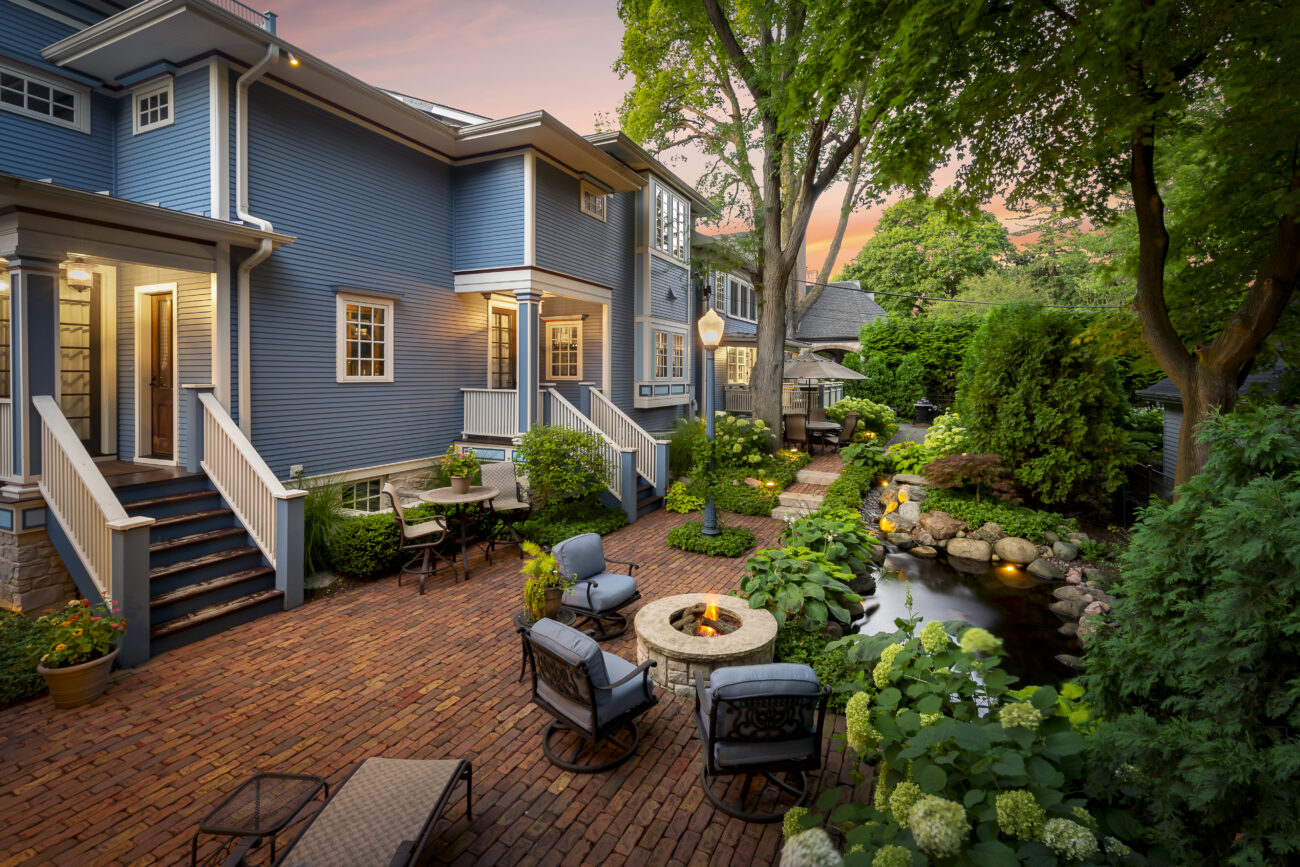 Backyard patio with fire feature and landscape lighting at dusk in Naperville, IL